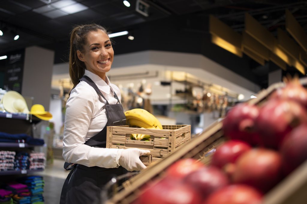 Supermarket worker supplying fruit department with food.